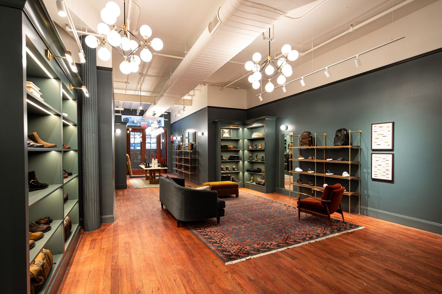 Modern office interior with wood floors, teal walls, and spherical pendant lighting.