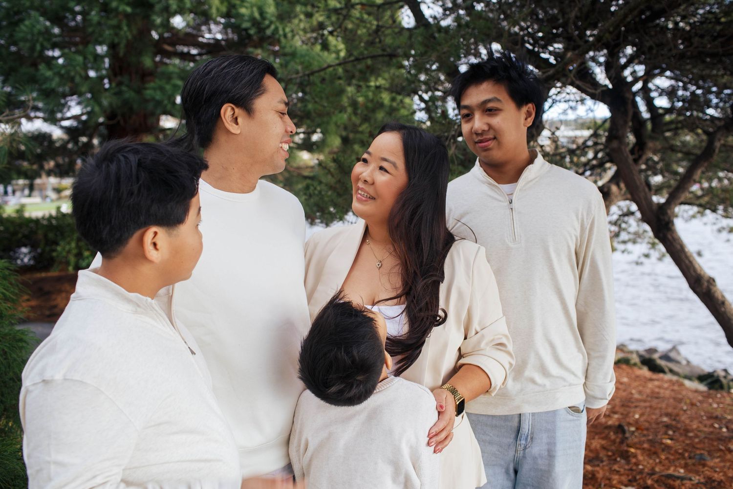 A family wearing white outfits shares joyful moments together during an outdoor photo session in Kirkland WA