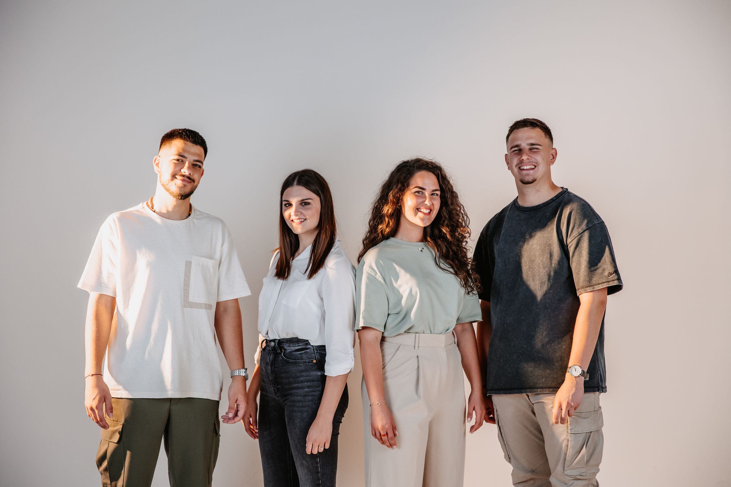 Four people in casual clothing pose against a white studio backdrop.