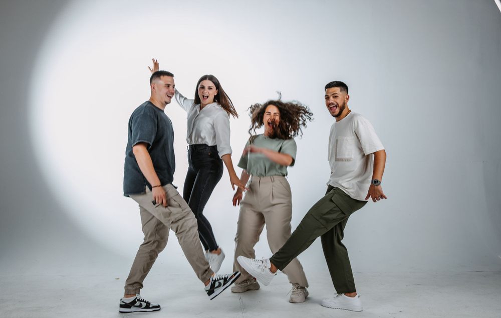 A playful group strikes dynamic poses in a studio with dramatic lighting.
