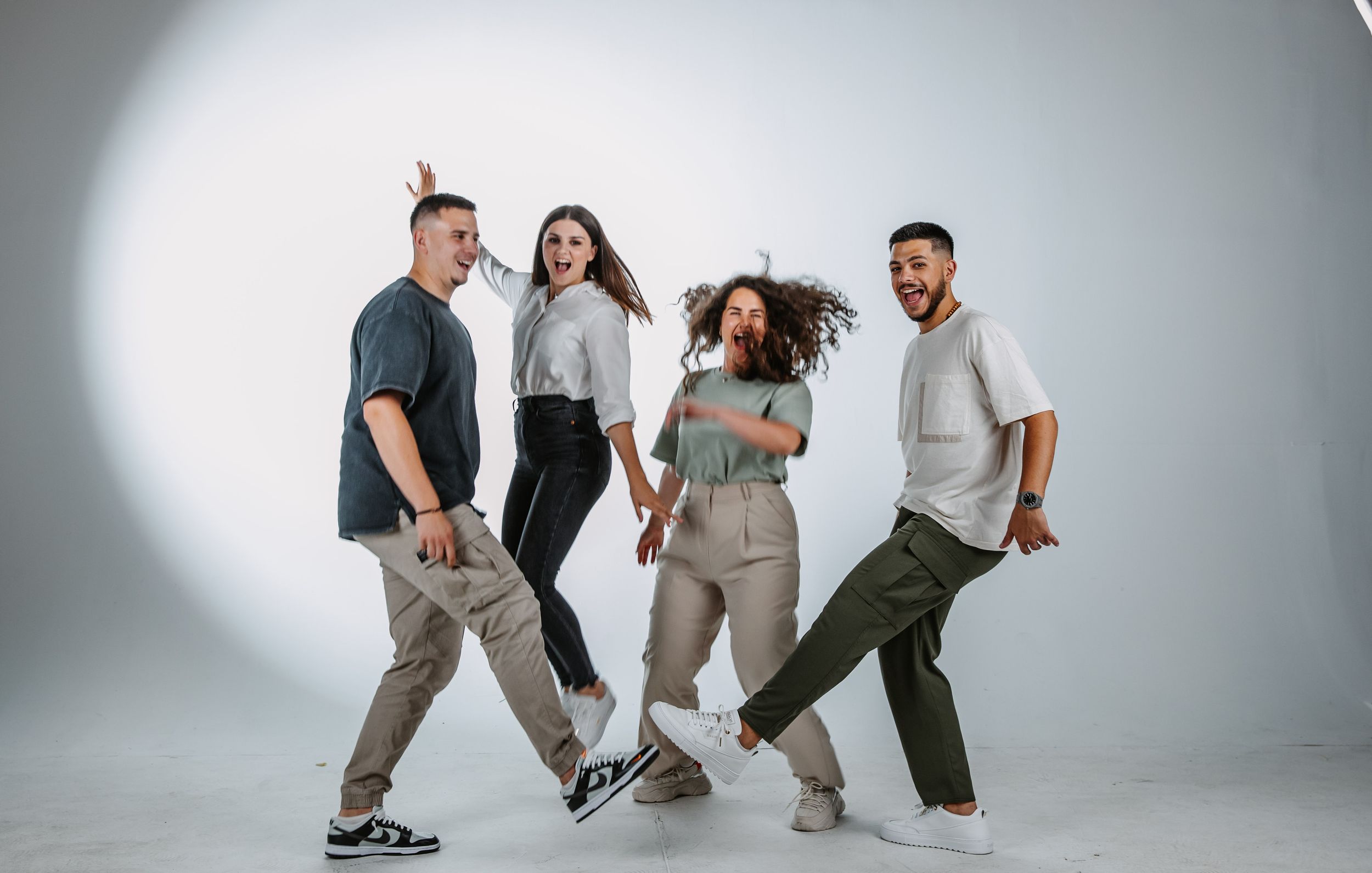 A playful group strikes dynamic poses in a studio with dramatic lighting.