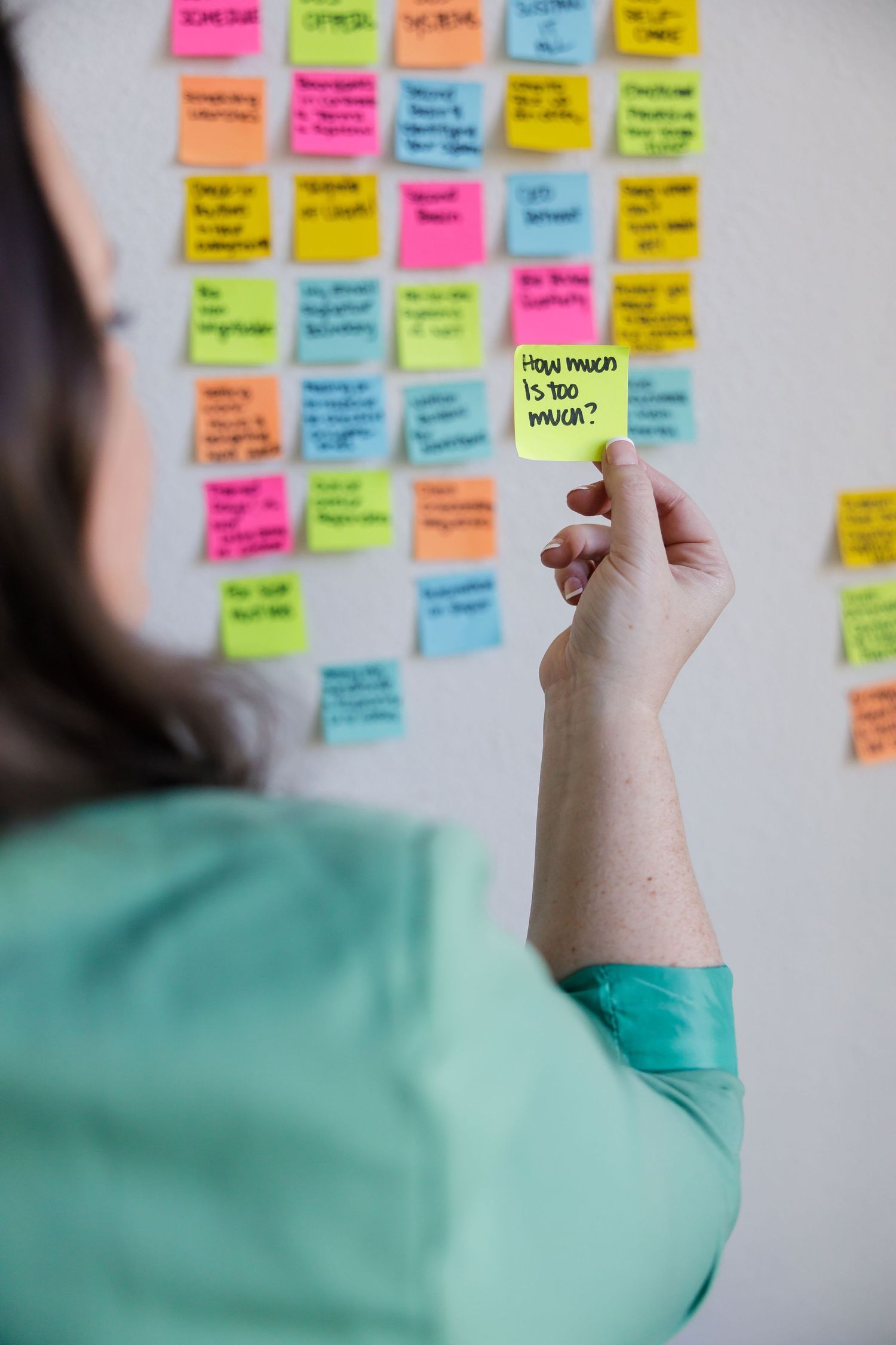 Woman burnout coach in Tacoma, WA GRLS Studio Personal branding photoshoot postit notes on wall "How much is too much?"