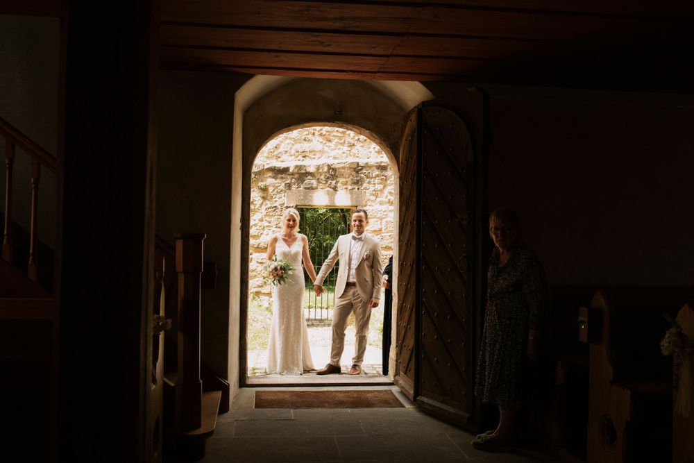 Dark silhouette of wedding ceremony guests framed by stone archway.