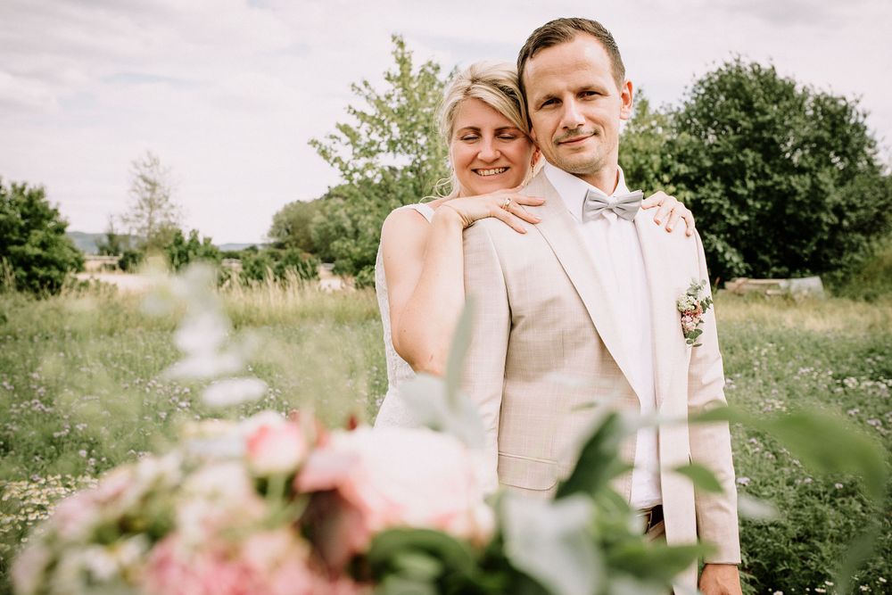 Romantic outdoor wedding portraits in a sunny field with soft natural lighting.