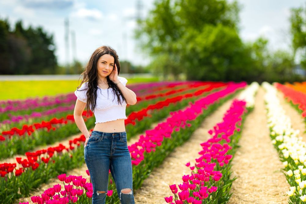 Person standing between vibrant rows of pink and red tulips in a springtime flower field. Ottawa Wedding Photographer