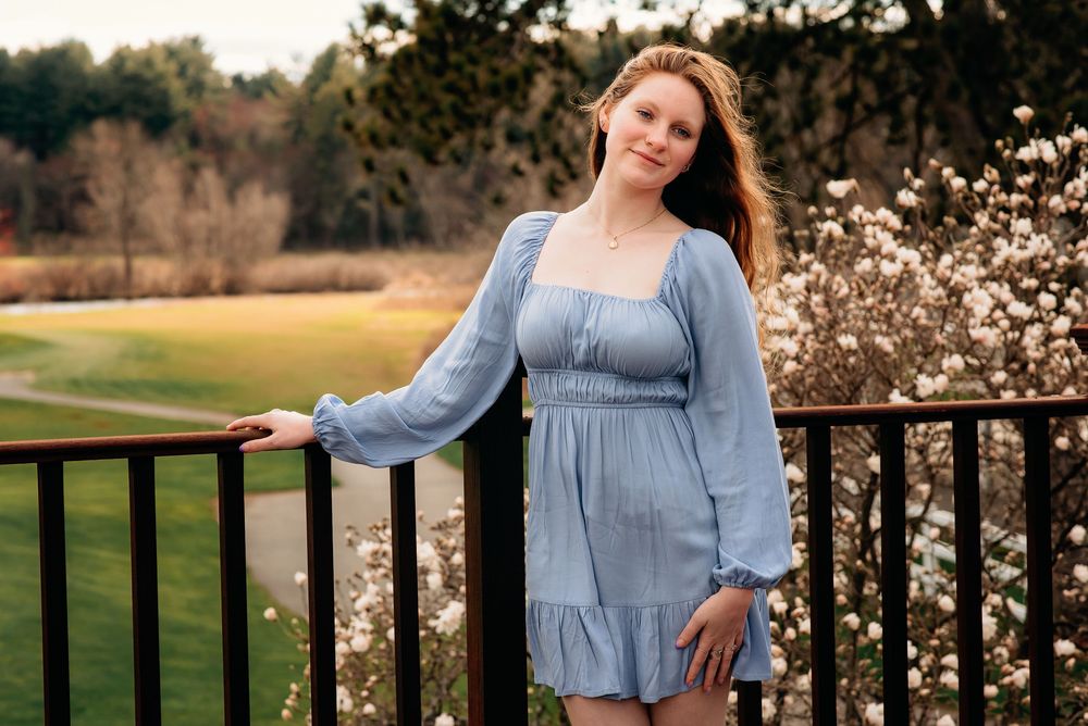 a college graduate posing in front of spring flowering bushes