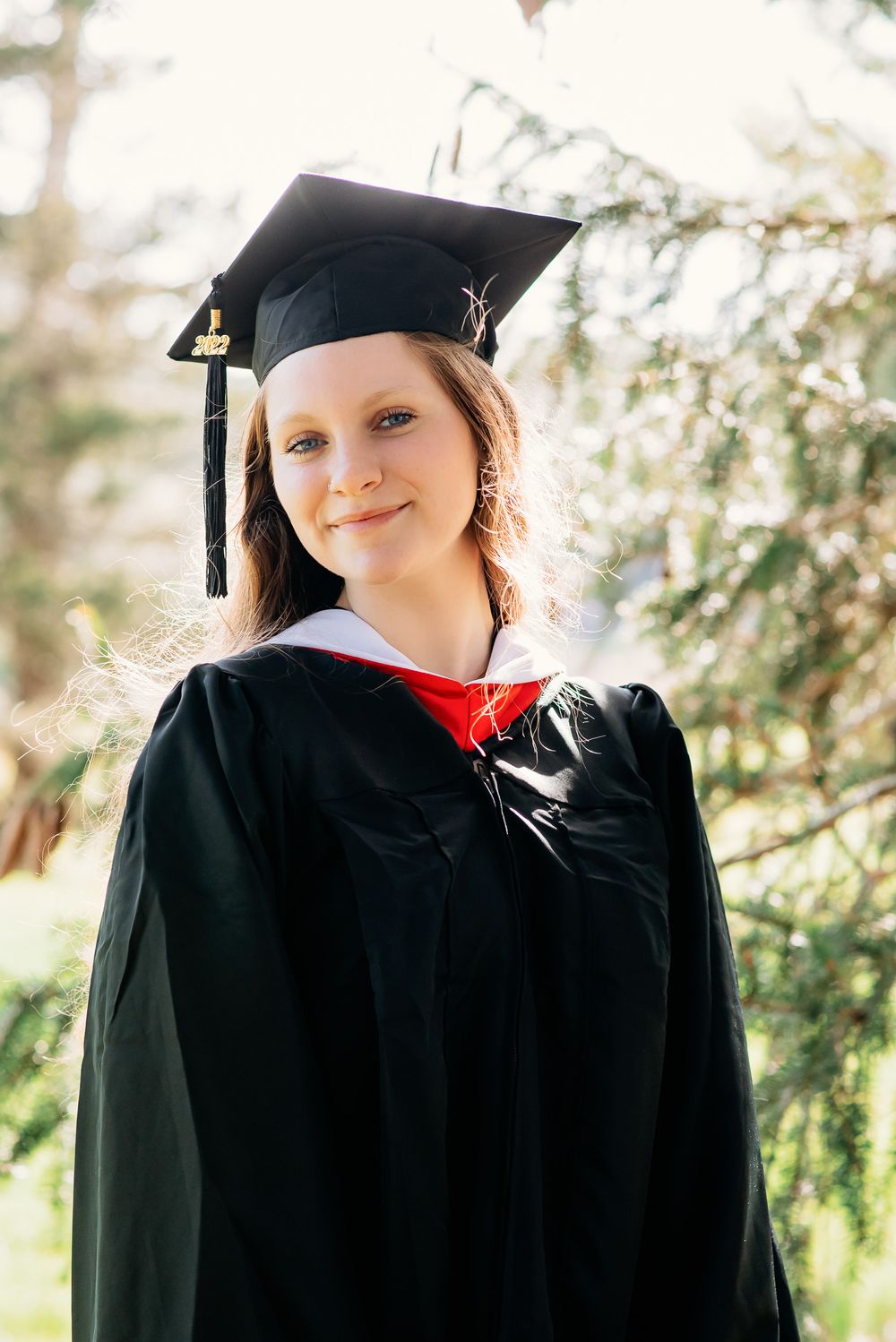 college graduate posed in cap and gown in outdoor portrait session