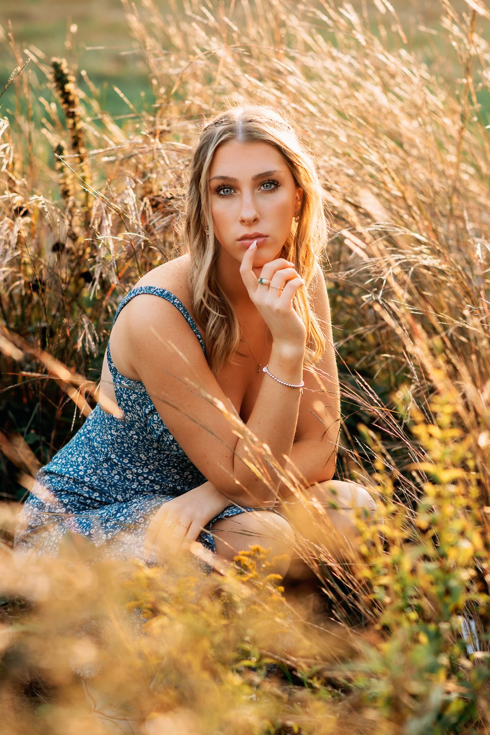 a Teen girl squatting in beautiful ornamental grasses in Marlborough Senior Portrait session