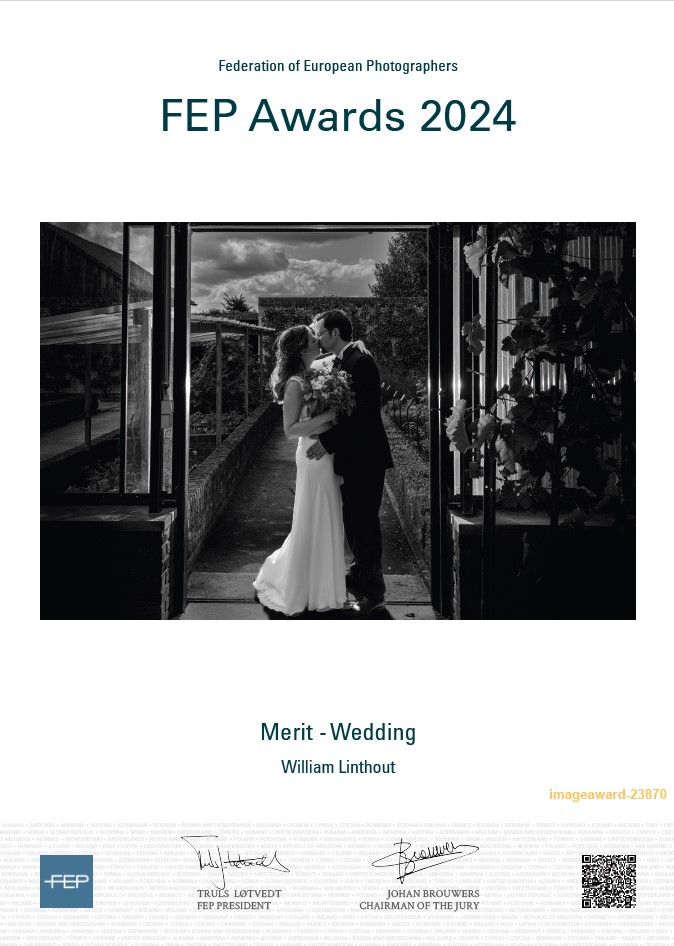 A black and white award-winning wedding photograph showing a couple in silhouette against glass windows.