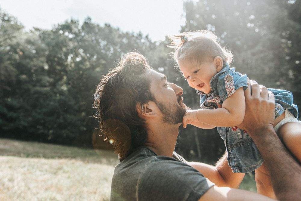 Heartwarming moment between parent and child playing in sunlit field.