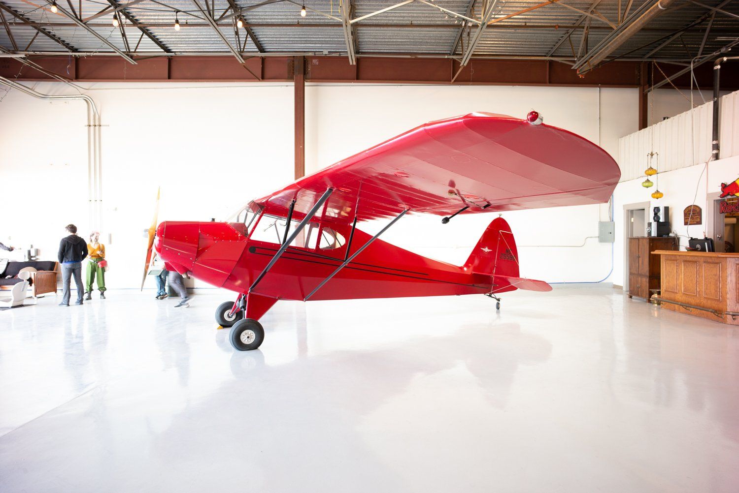 Bright red vintage aircraft displayed inside hangar with polished floor.