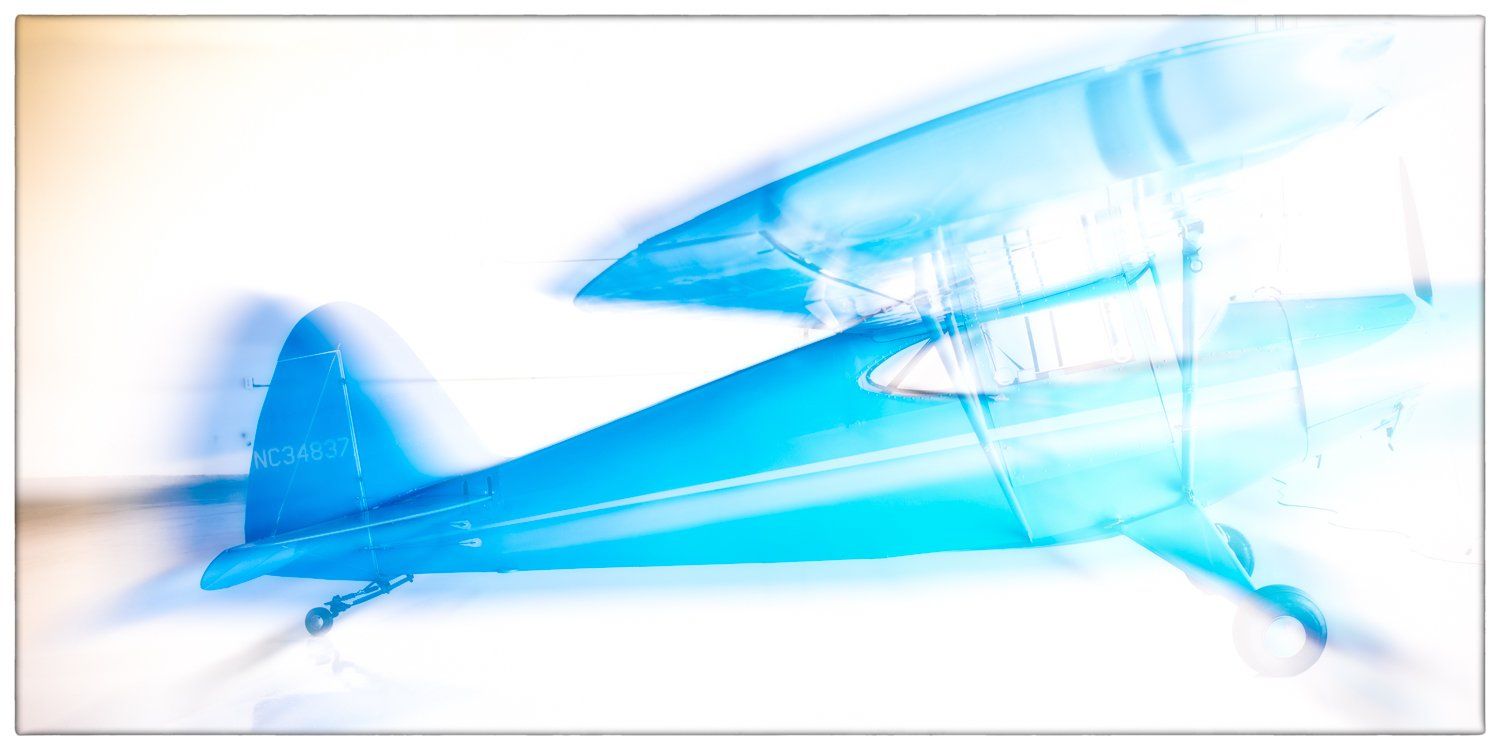 Blue vintage airplane illustration rendered with a soft ethereal effect against white background.