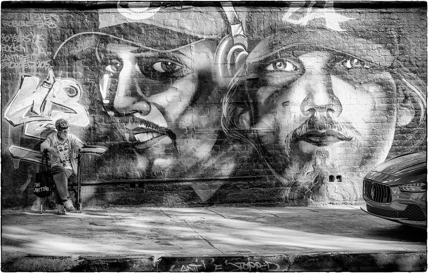 Black and white street art mural featuring dramatic faces painted on urban wall.