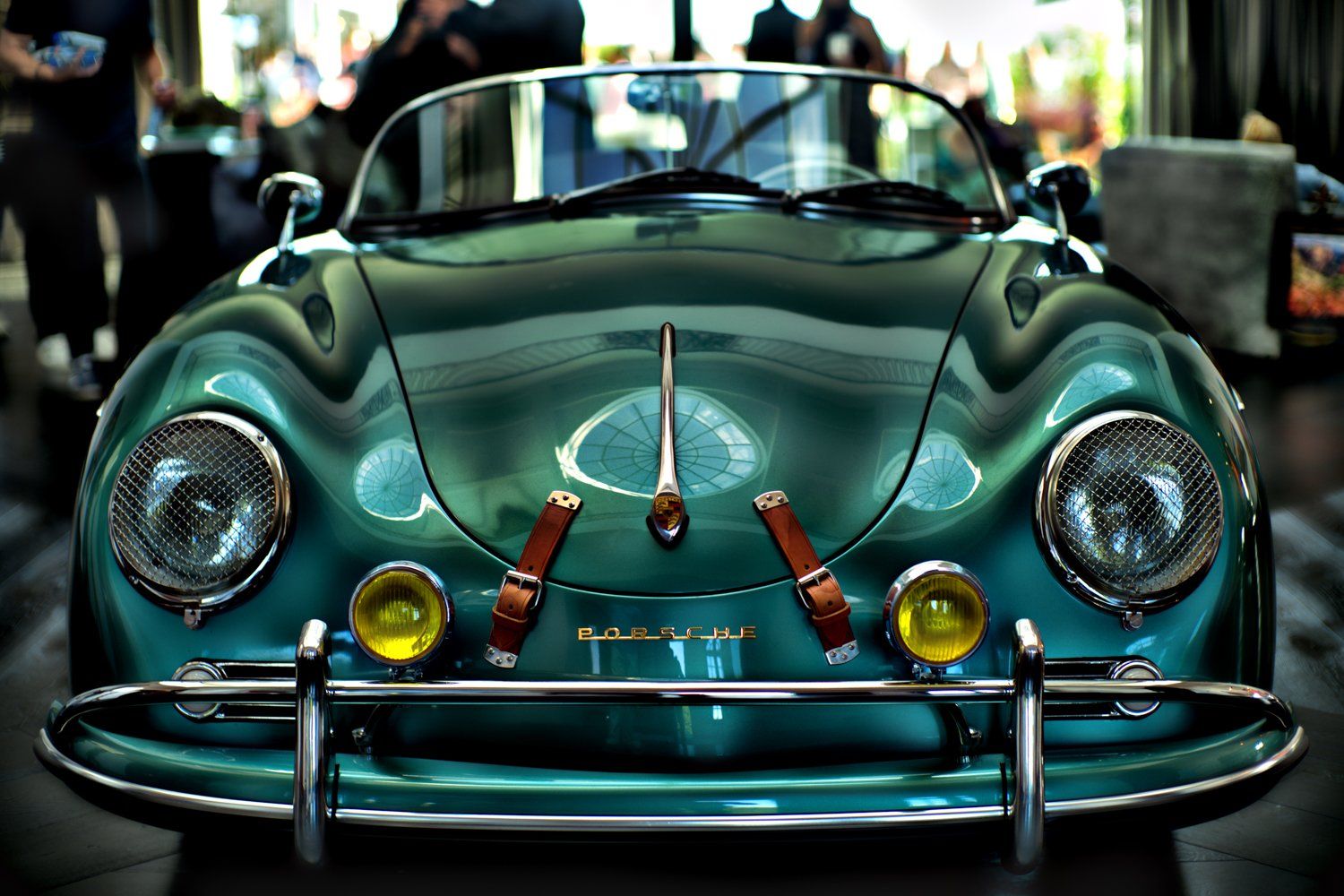 Classic turquoise Porsche 356 sports car with distinctive round headlights and chrome bumper.