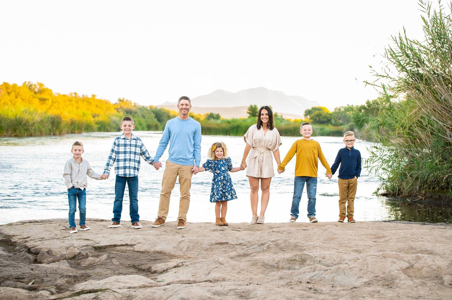 Family of 7 poses near the Salt River at sunrise with mountains in the background during their Arizona family vacation photo session.