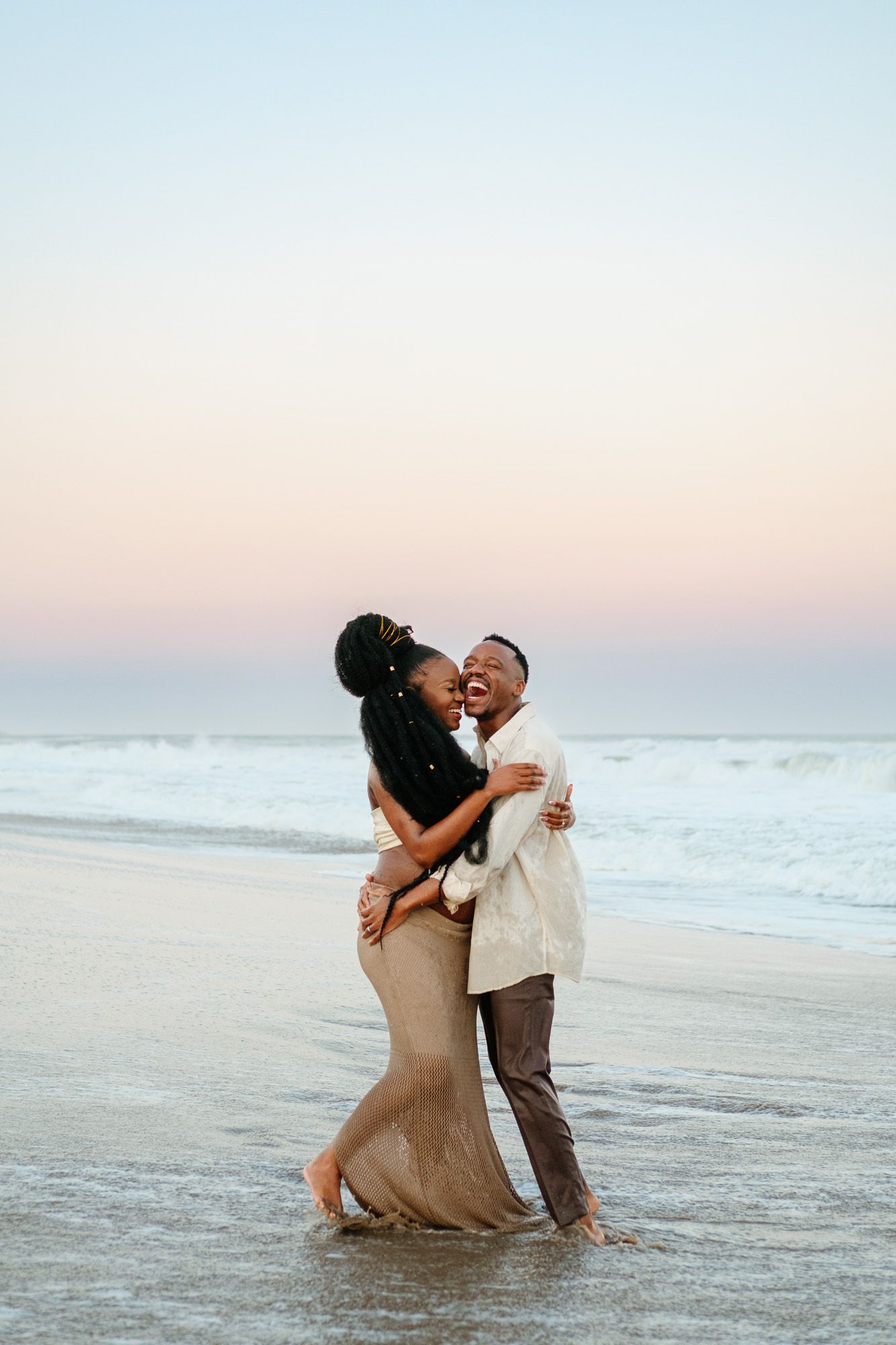 Expecting parents laughing and connecting in the water at Mtunzini Beach