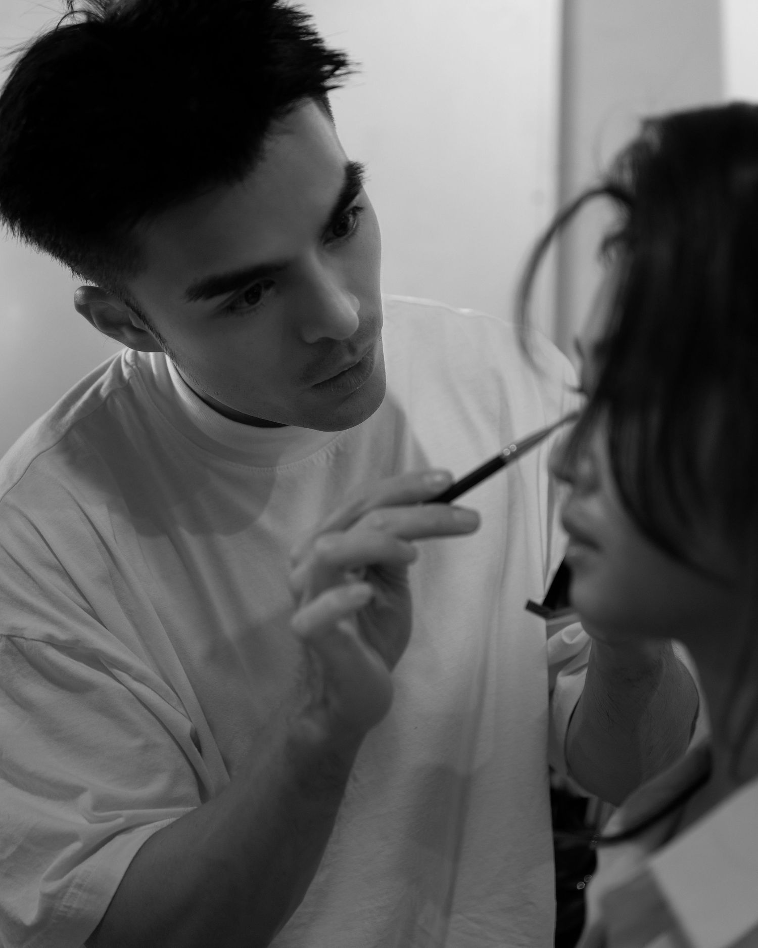 Black and white photo of makeup artist applying makeup to a woman.