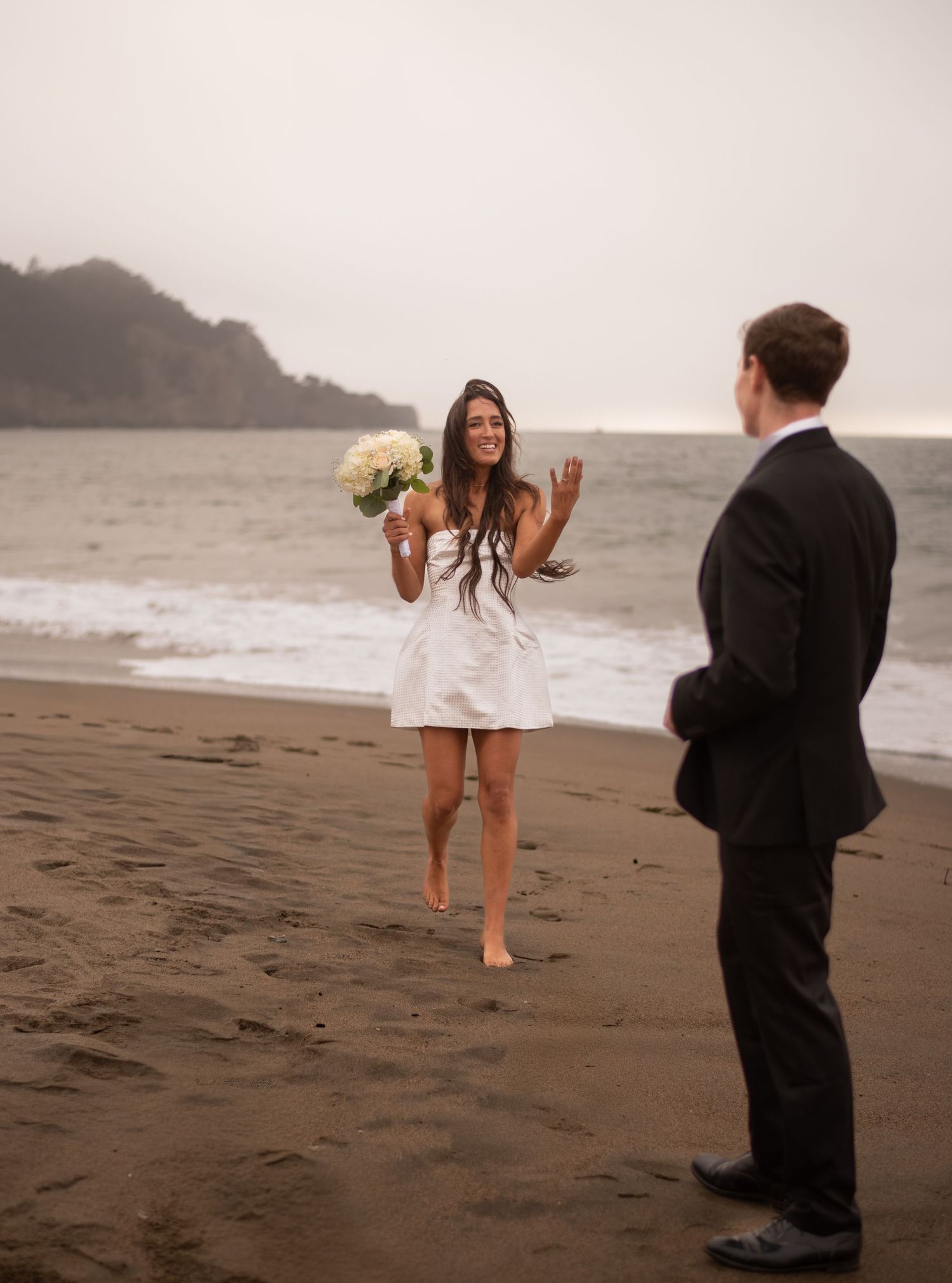 An intimate beach elopement with the Golden Gate behind them—windy, wild, romantic, and completely in the moment.