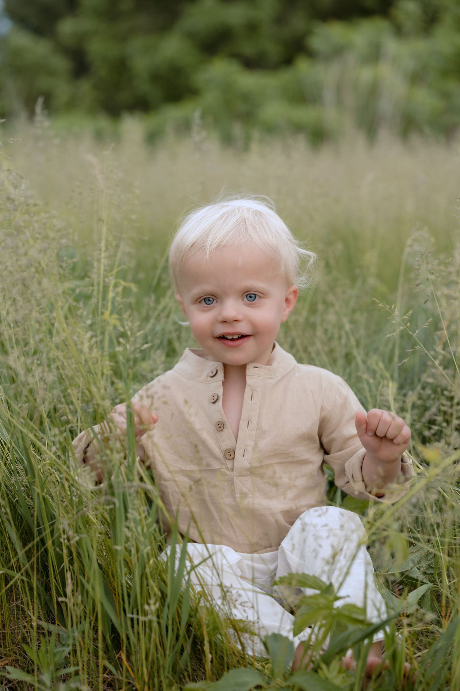 Toddler sits in grassy field for an individual headshot during family photos in Hudson, WI.
