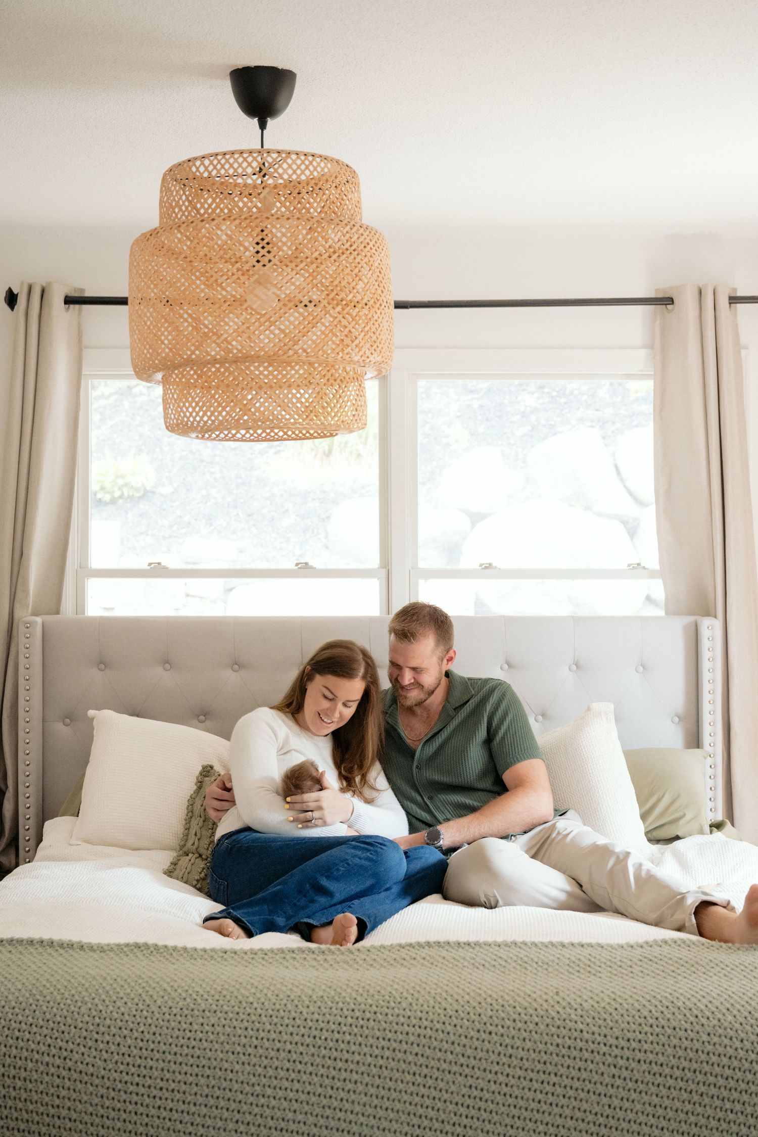 Parents snuggle on their bed during in-home lifestyle newborn portraits in Minnetonka, MN.
