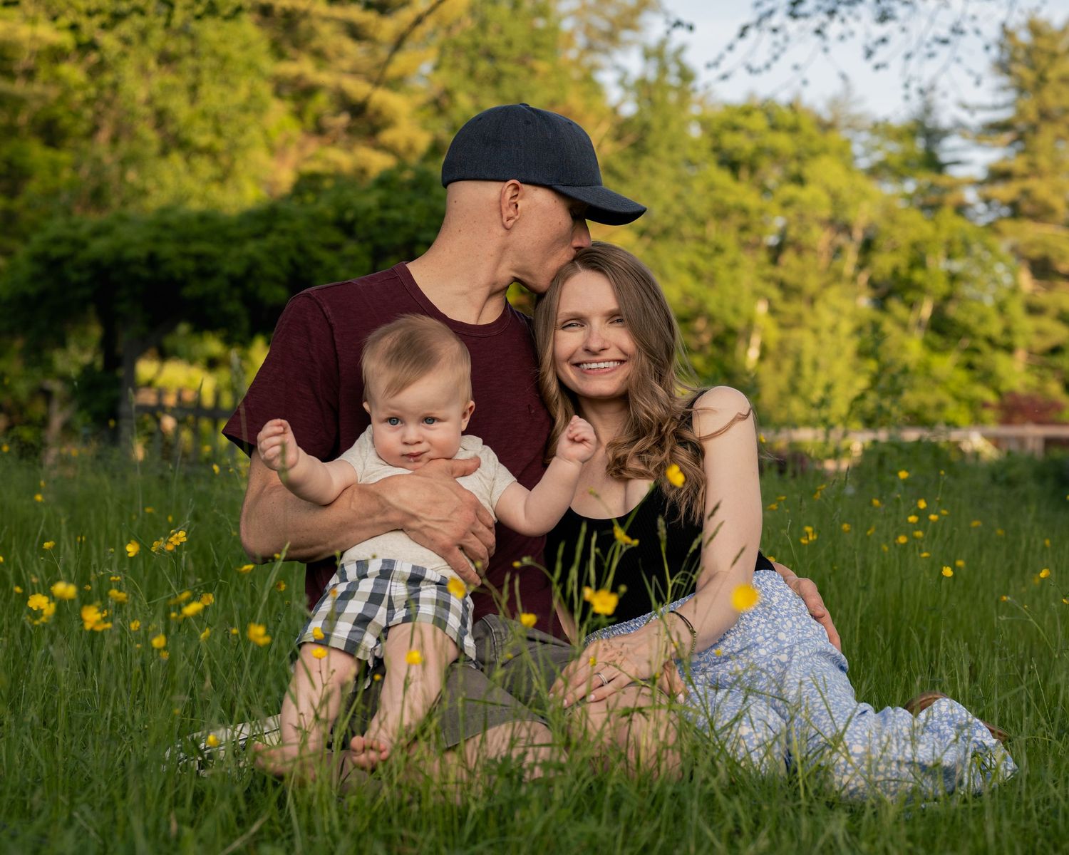Young family sits together at a family photoshoot in a field in the Merrimack Valley.