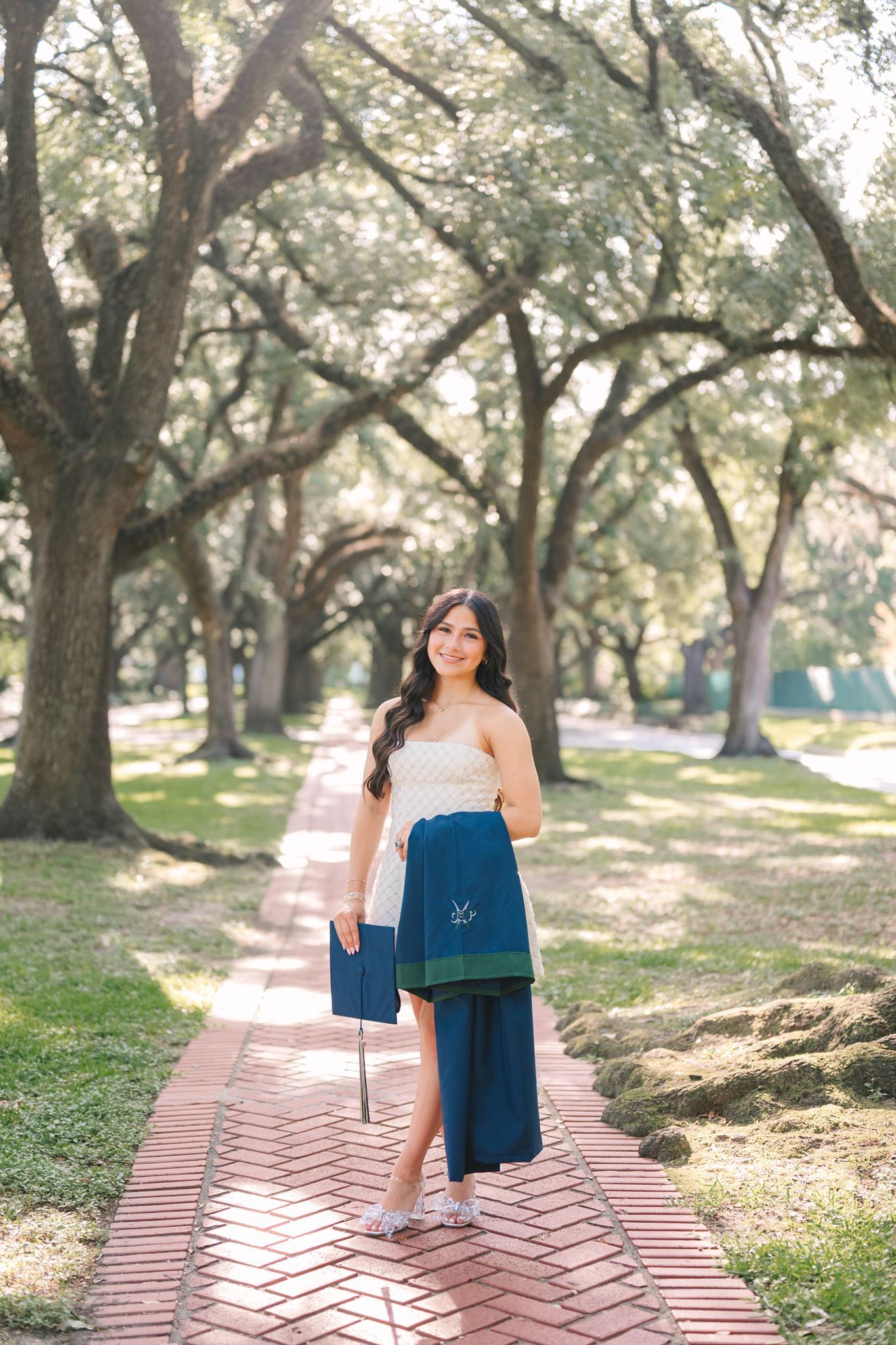 College Park High School senior girl, wearing short white dress, standing under oak tree canopy in Houston Texas.