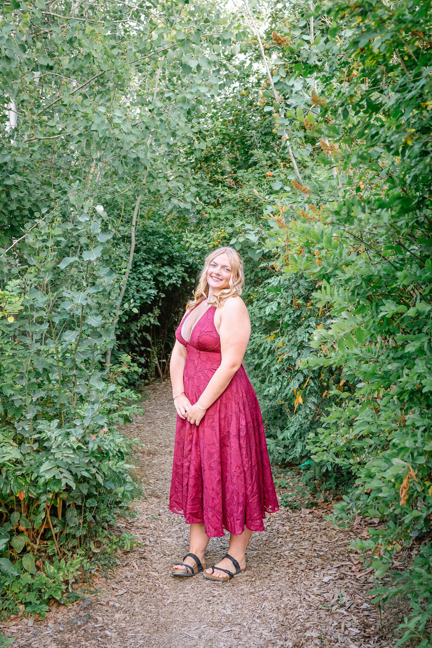 Full-length senior portrait on a tree-lined pathway at Olympic Sculpture Park in Seattle Washington.