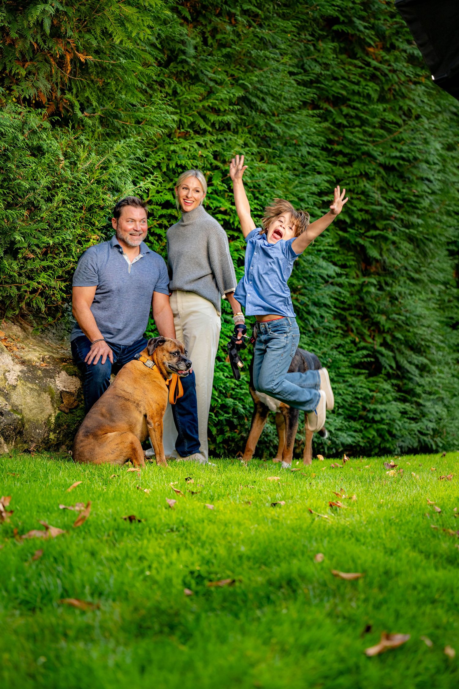 Family of four holding hands walking on a path surrounded by vibrant autumn foliage in a park.