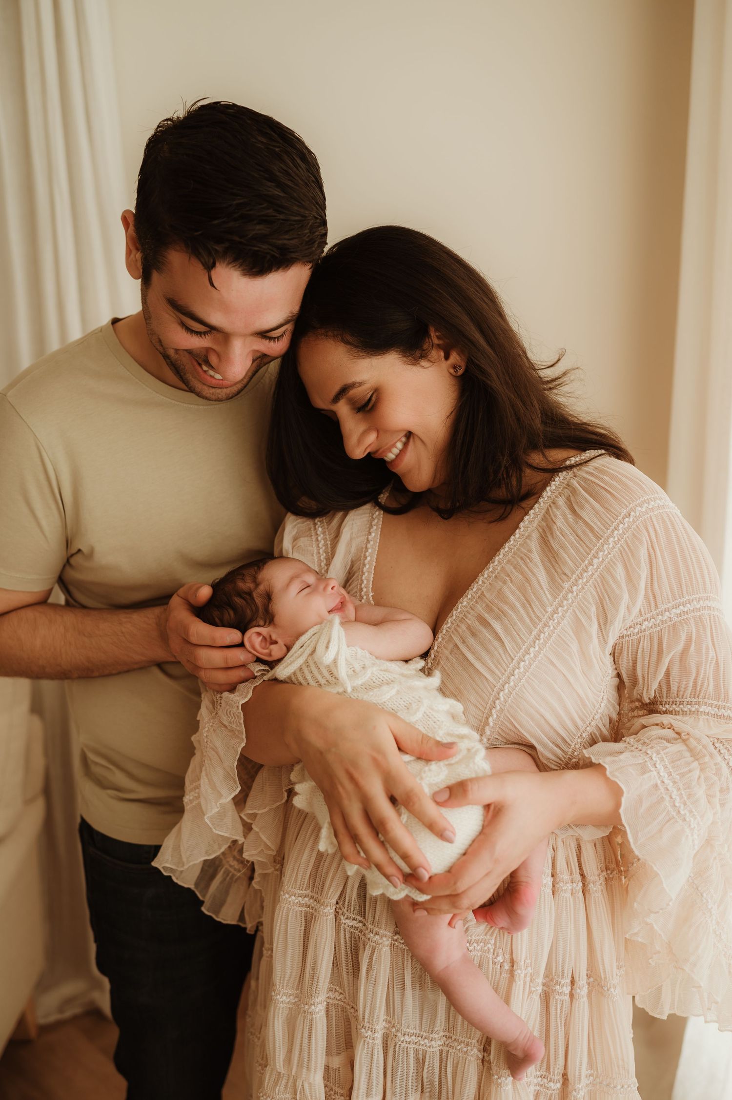 Peaceful sleeping newborn wrapped in soft white blanket while being cradled in loving arms.