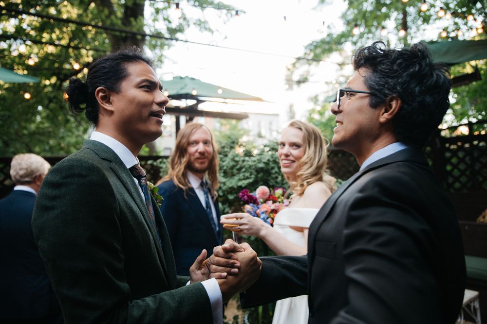 Wedding guests celebrate with the couple during an outdoor garden reception.