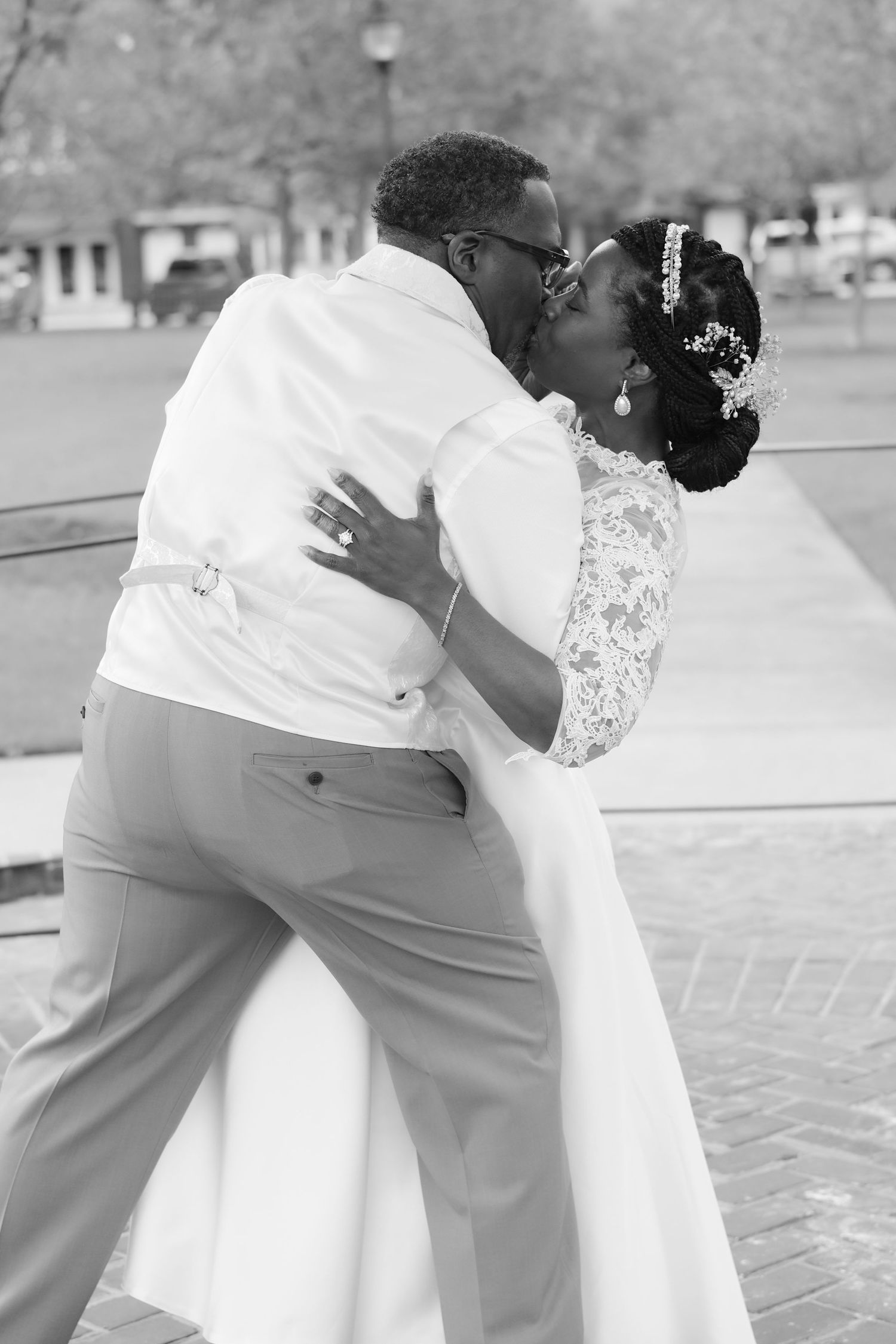 Man in white shirt kissing woman's hand outdoors, woman with red hair smiling warmly.