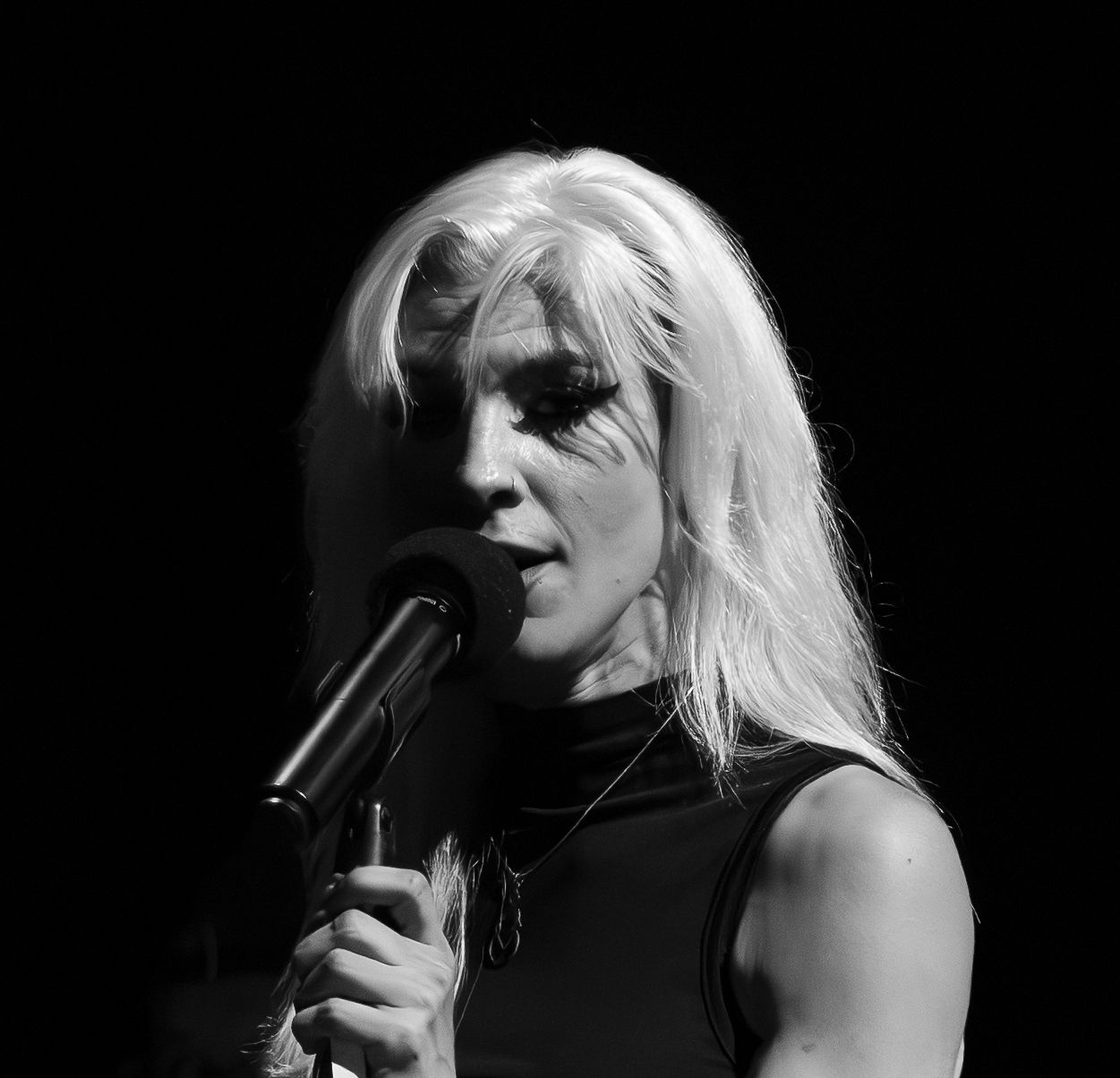 Black and white photo of a blonde female singer performing on stage with a microphone.