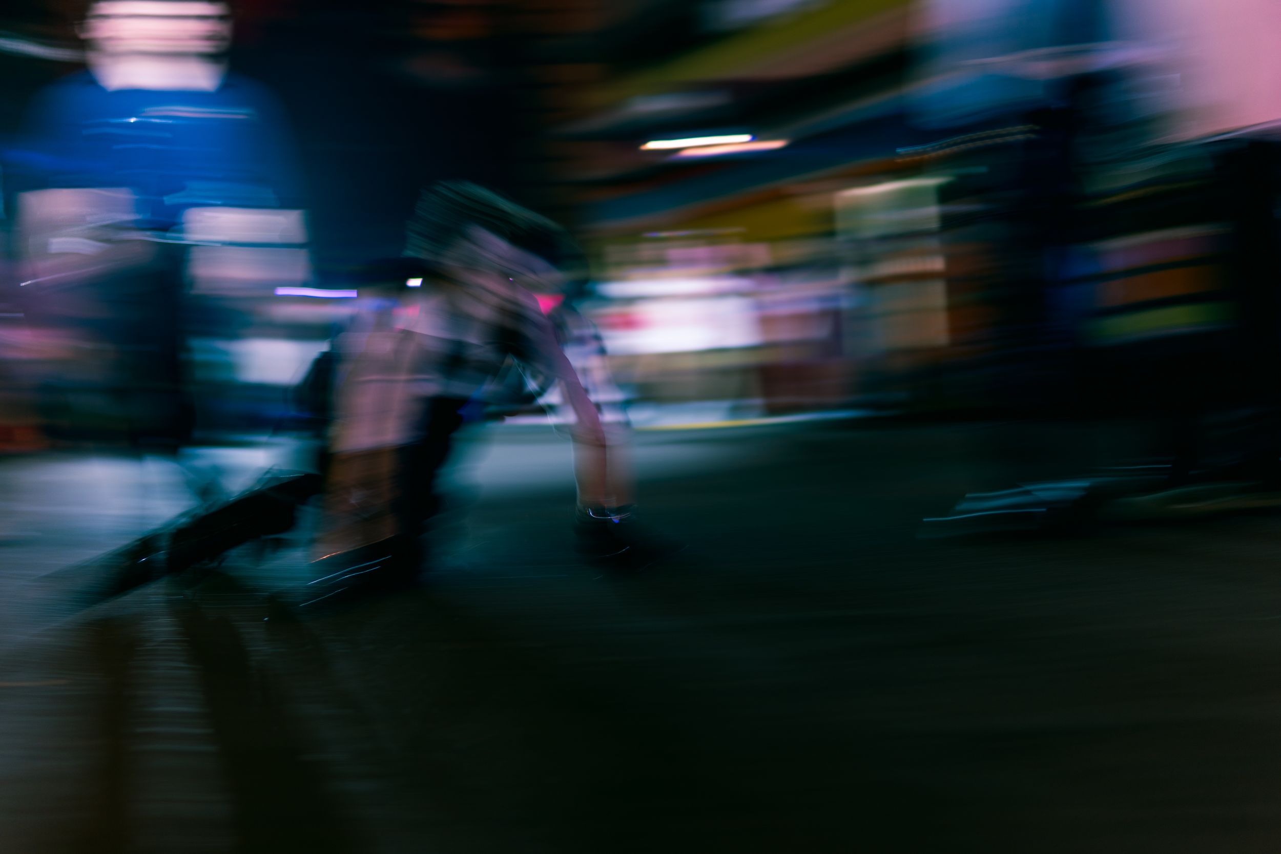 Blurred motion shot of performers in costume running through dark Halloween carnival at night.