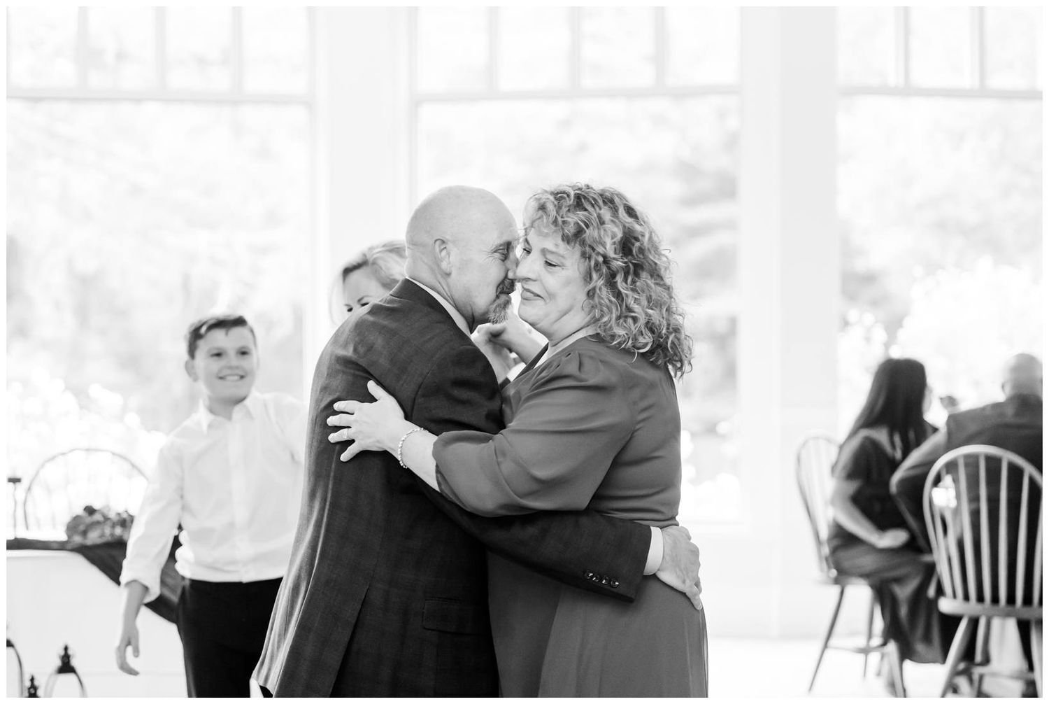 Emotional black and white photo of groom sharing tender dance with mother at wedding reception.