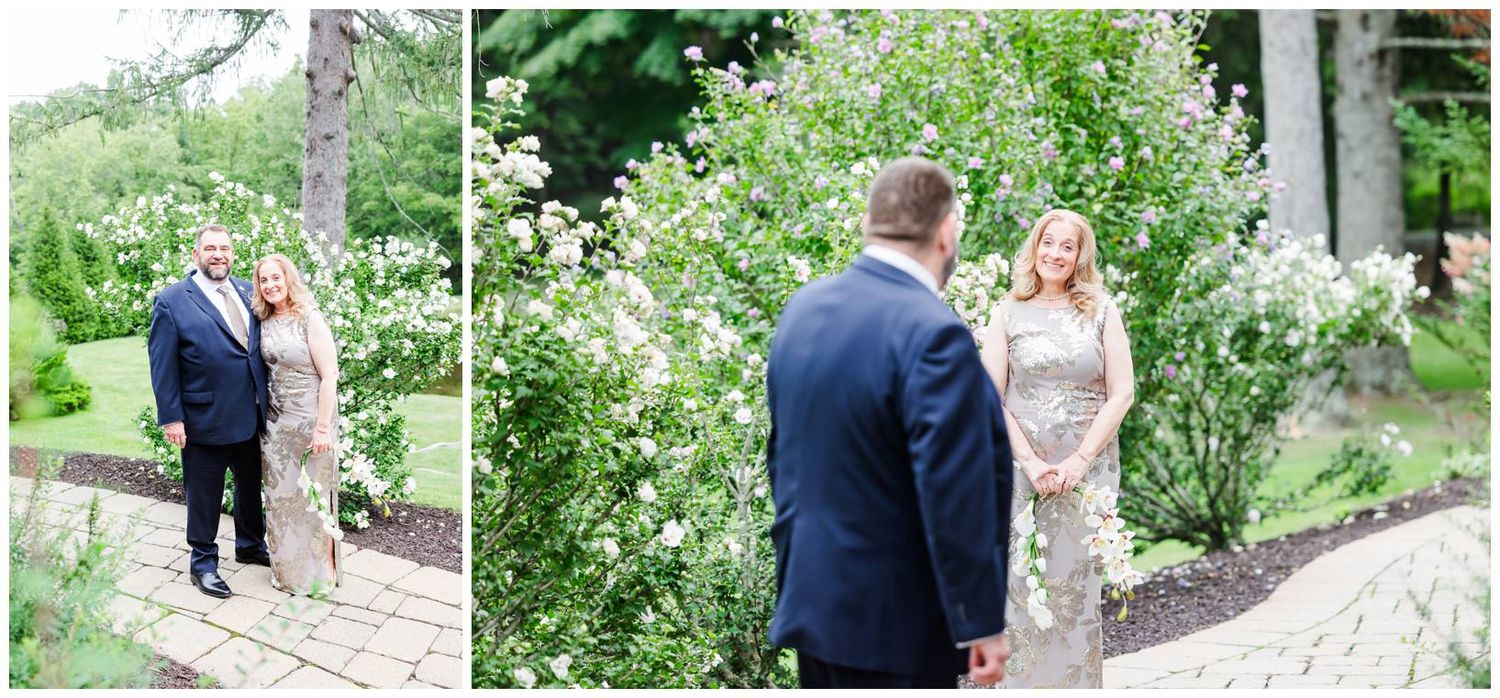 Couple poses together near blooming white flowers in a lush garden during an outdoor engagement session.