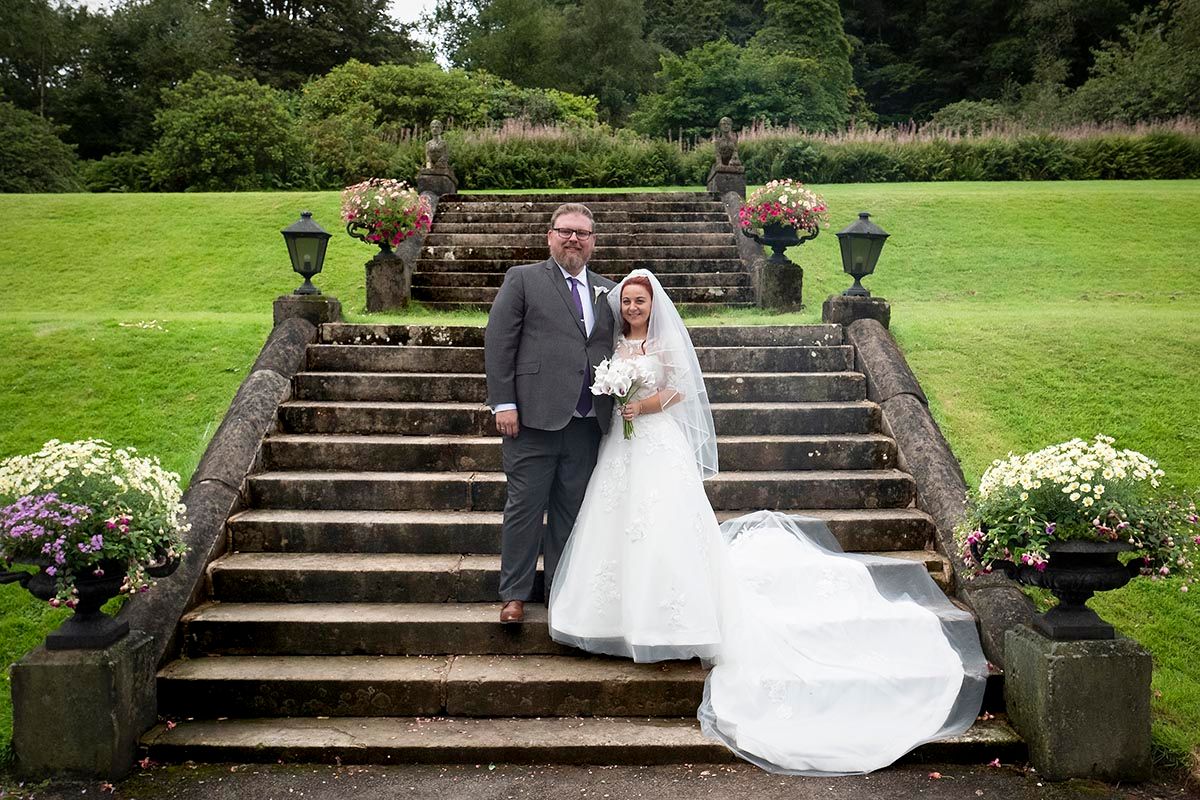Bride and groom posing on stone steps at Auchen Castle wedding venue