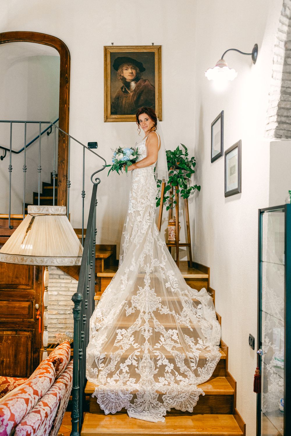 La sposa scende le scale con il lungo abito visto da dietro.