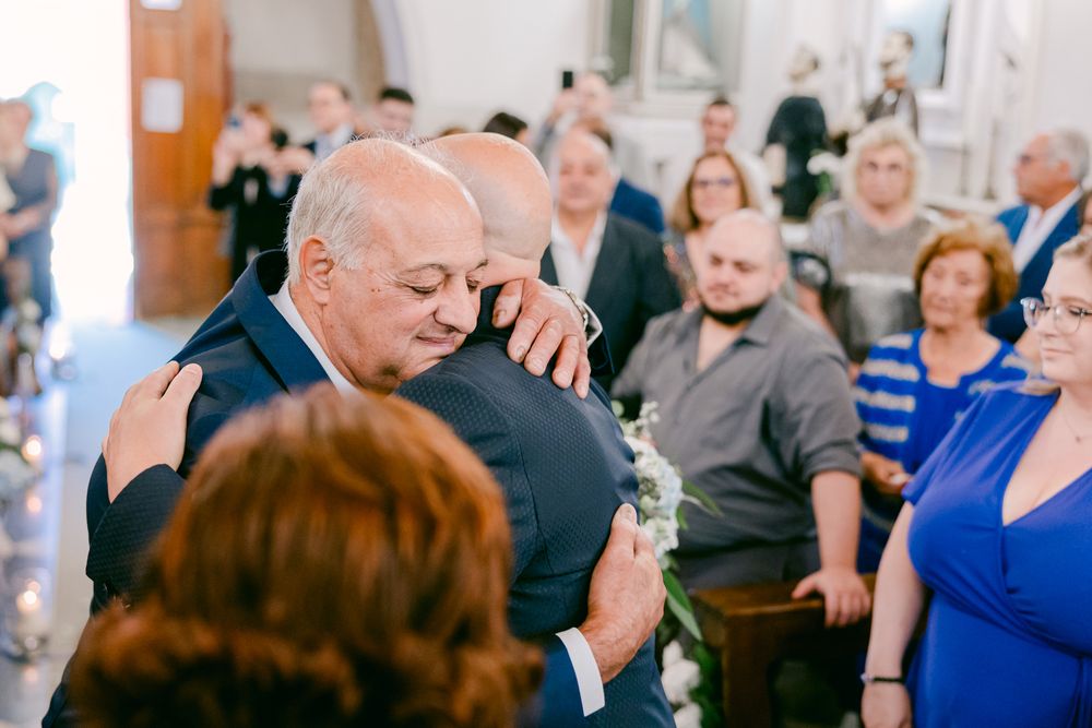 Lo sposo abbraccia un invitato tra le persone riunite.