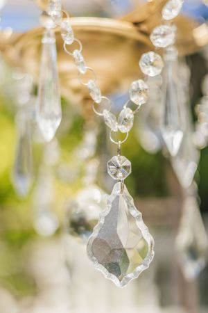 Close-up of elegant crystal chandelier pendants with sparkling glass drops and beaded chains against a soft bokeh background.