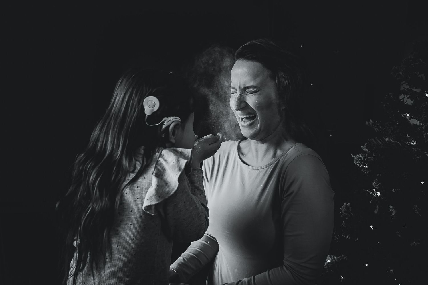 Mother laughing as her daughter playfully blows flour in her face during a storytelling baking photoshoot in Woerden, Utrecht.