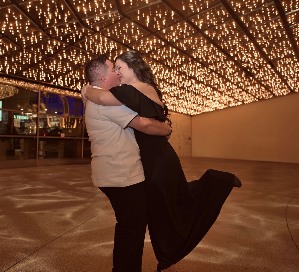 Man lifting woman joyfully under a breathtaking ceiling of twinkling lights in Las Vegas.