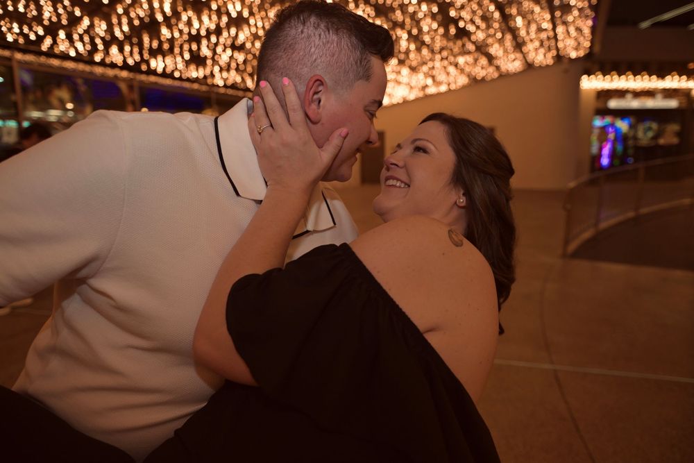 Couple sharing a romantic moment at an elegant evening event with warm string lights glowing in the background.