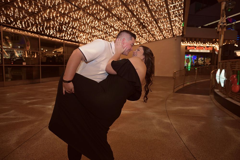 Couple sharing a romantic dip kiss at night under sparkling fairy lights in Las Vegas.