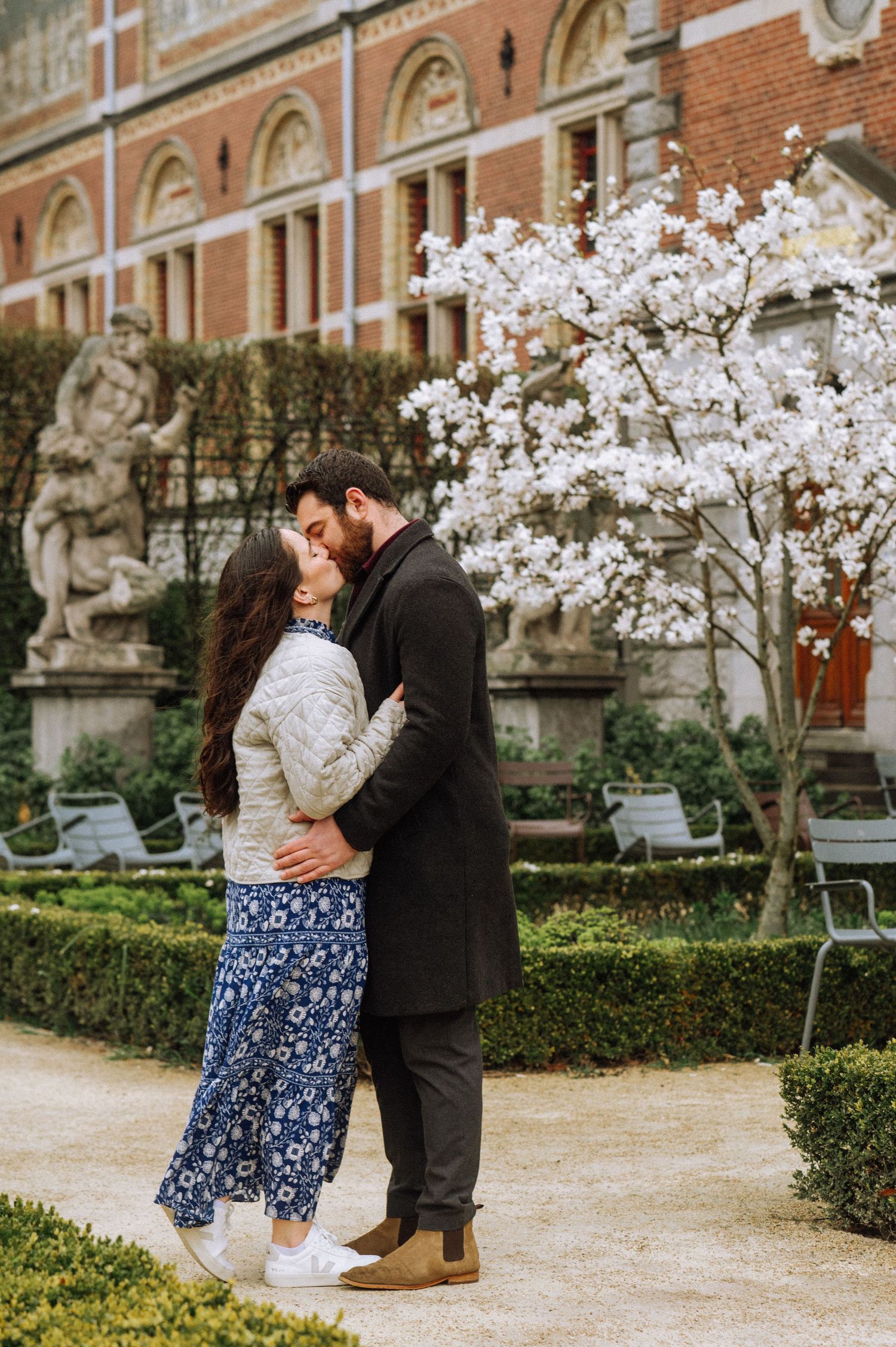 Couple embracing and kissing in a garden beside a blooming magnolia tree, Rijksmuseum, Amsterdam.
