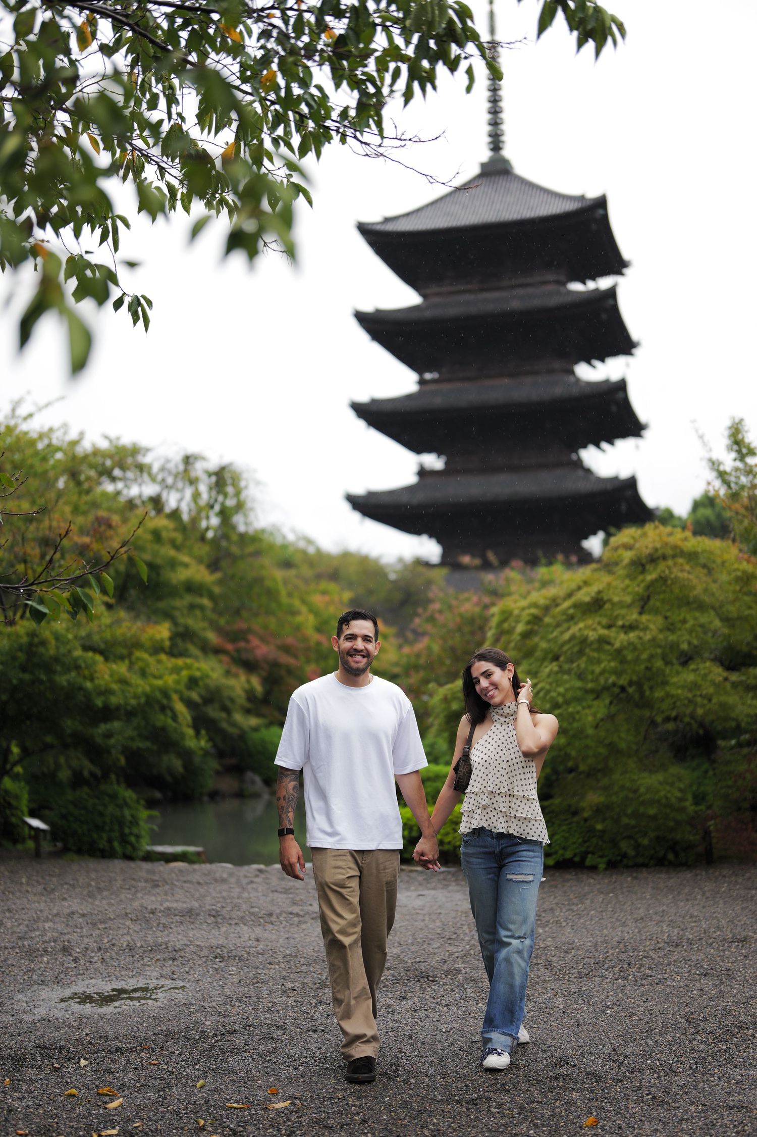 Couple in traditional Japanese kimono strolling hand in hand through a garden of autumn foliage with a five-story pagoda behind them.
