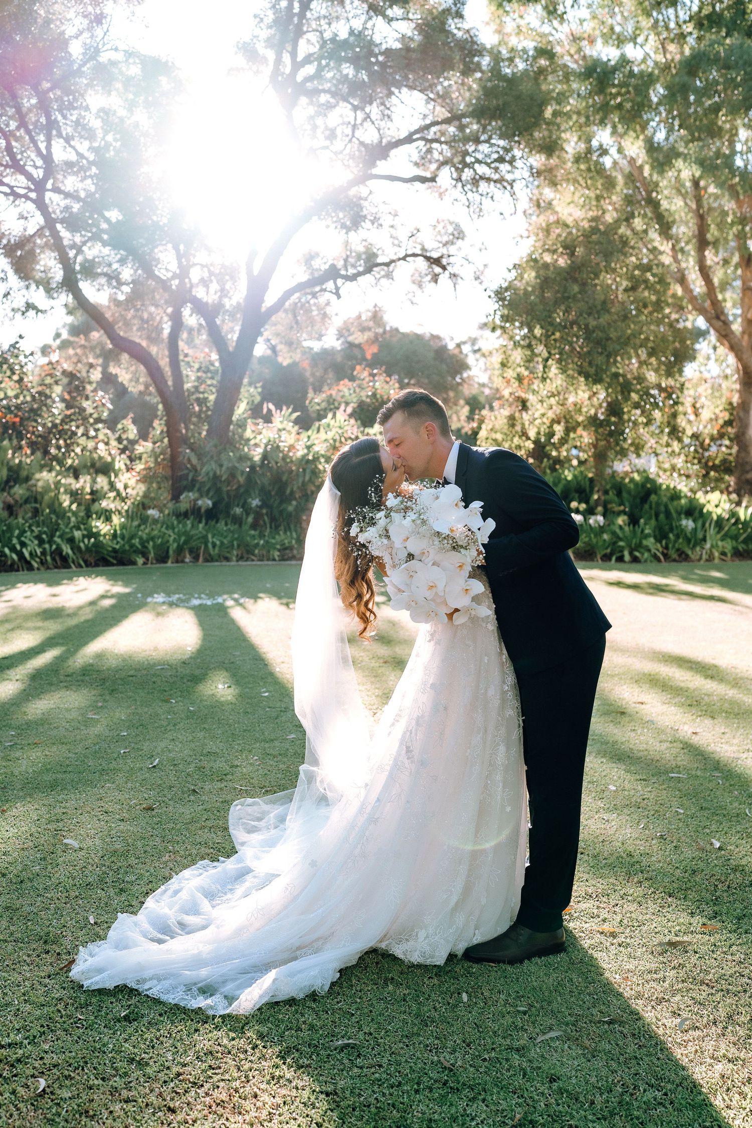 Bride in white strapless gown laughing with wedding coordinator in black dress outdoors.