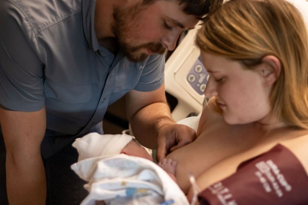 New parents lovingly gaze at their newborn baby in a hospital room shortly after birth.