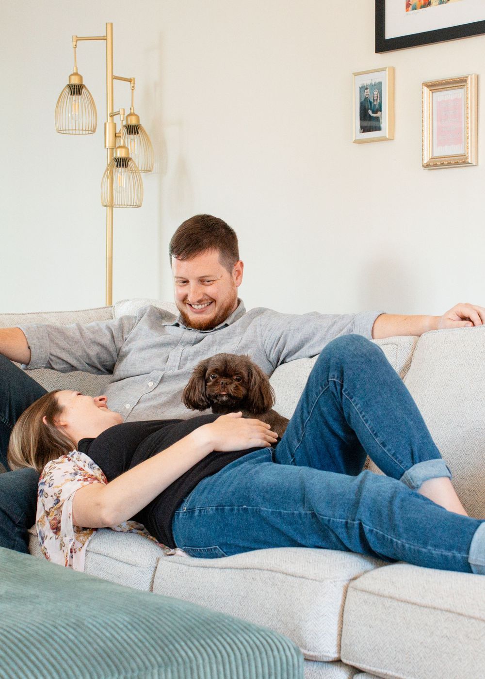 Hannah, David, and pet snuggling on couch during their in-home lifestyle maternity session in Flint, Michigan