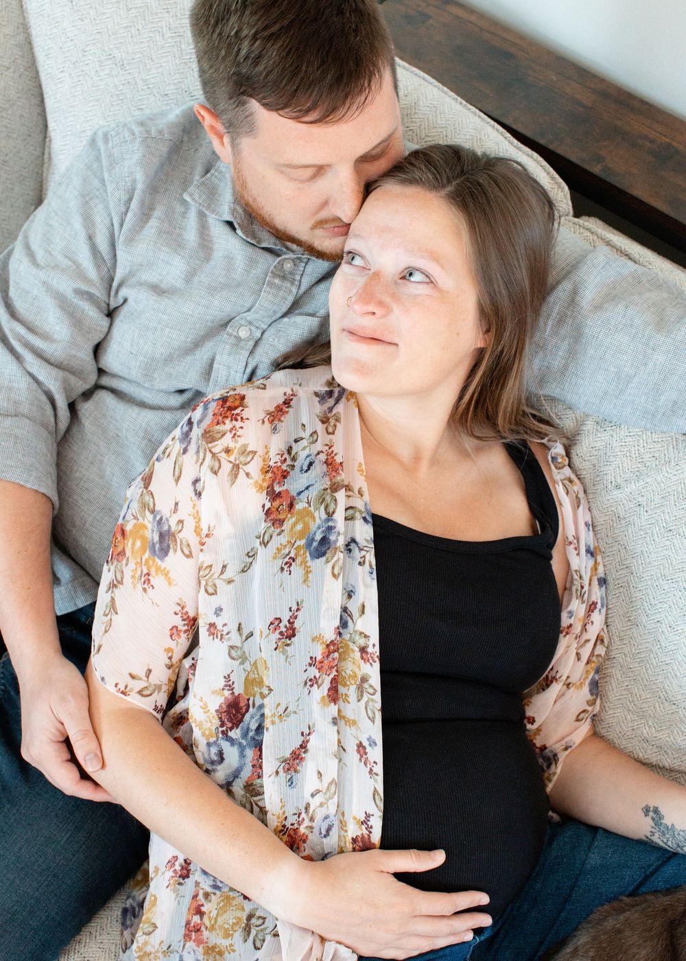 Hannah and David snuggling on couch during their in-home maternity session in Flint, Michigan