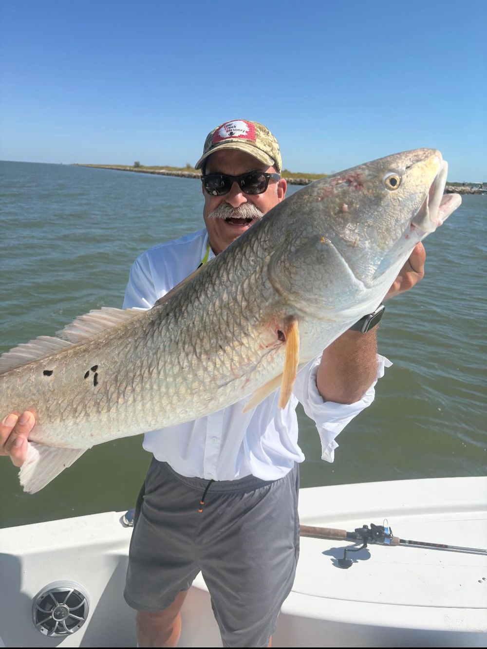 Angler proudly holds a large redfish caught on a fishing charter in Texas coastal waters.